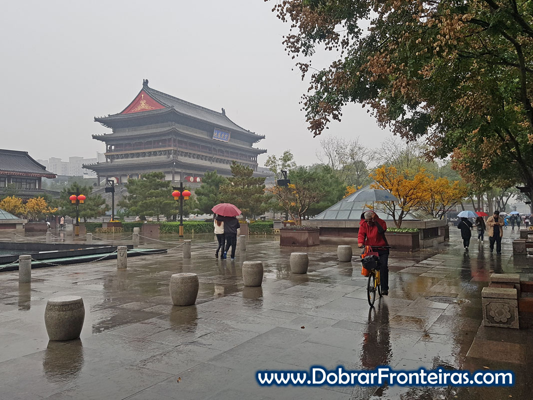 Homem de bicicleta à chuva junto à torre do tambor em Xian, China