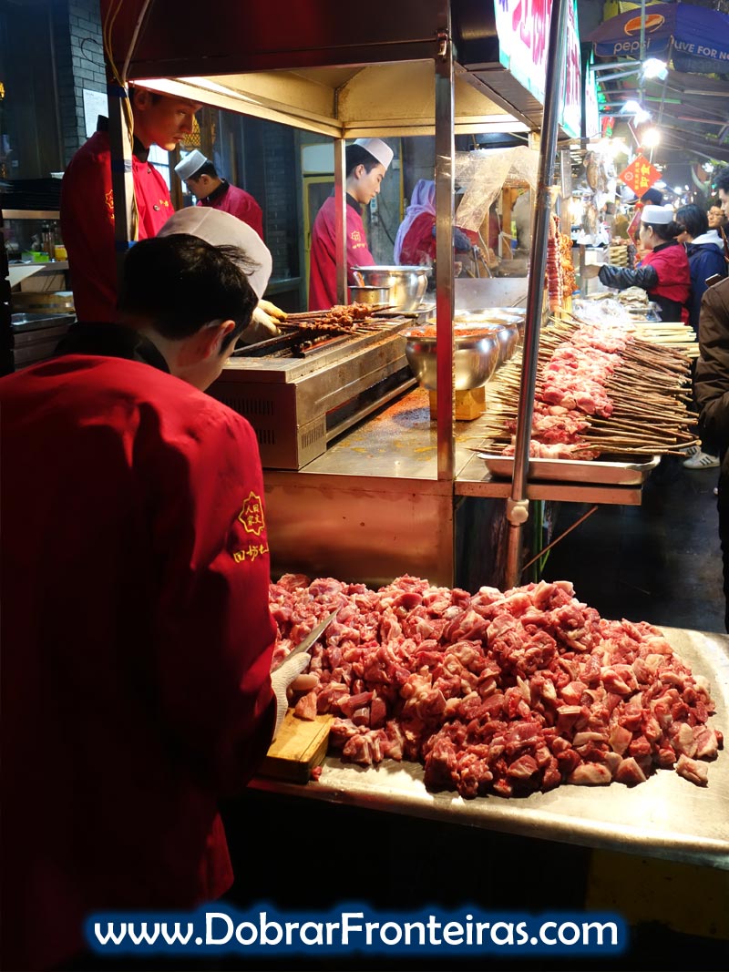 Rapaz prepara carne para as espetadas nas ruas de Xi'an, China