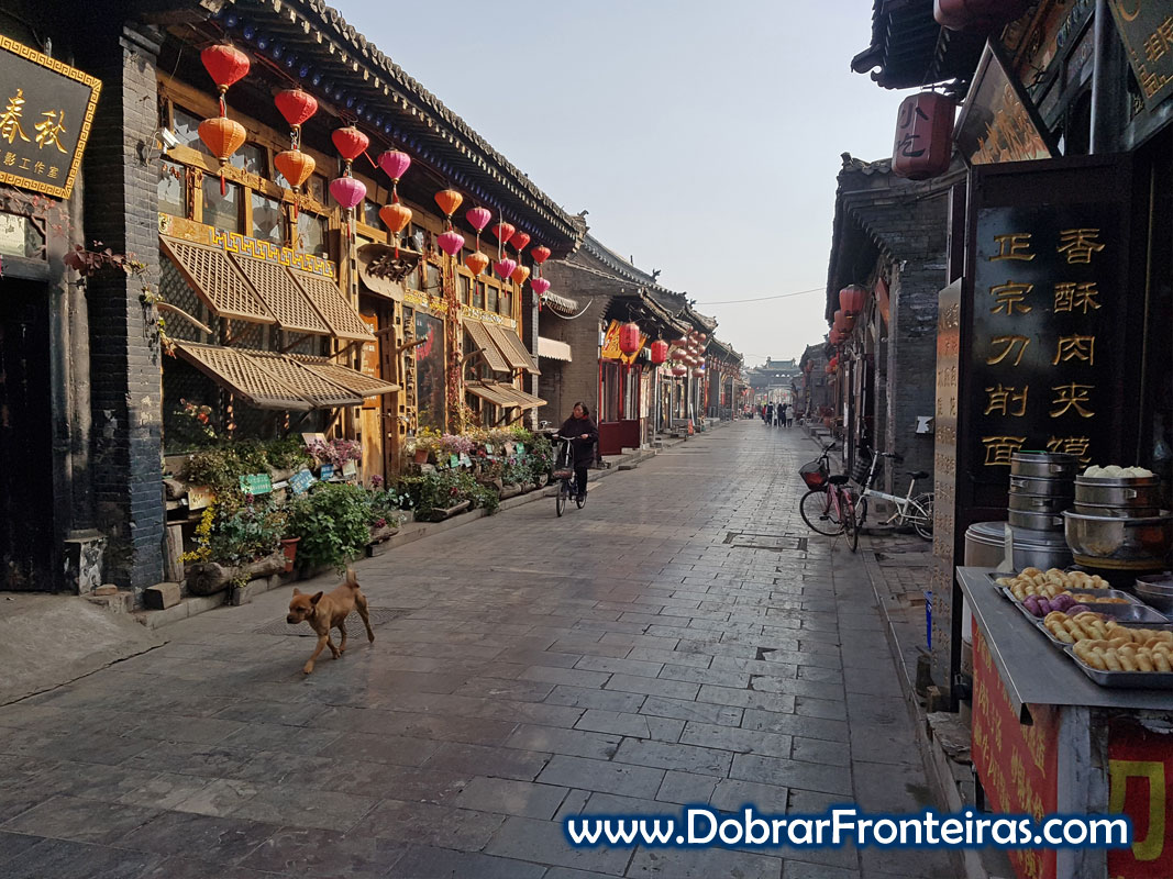 Rua ancestral chinesa em Pingyao com candeeiros vermelhos, cão e bicicleta .