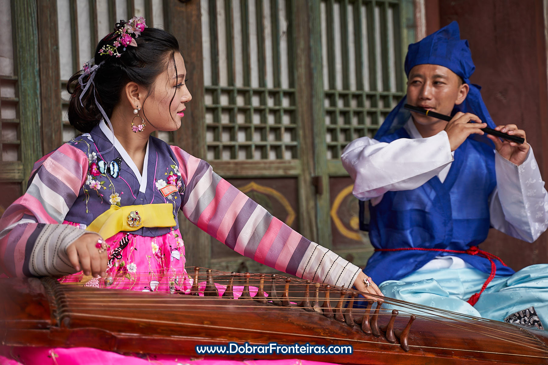 Casal de noivos com roupa tradicional da Coreia do Norte e instrumento musical