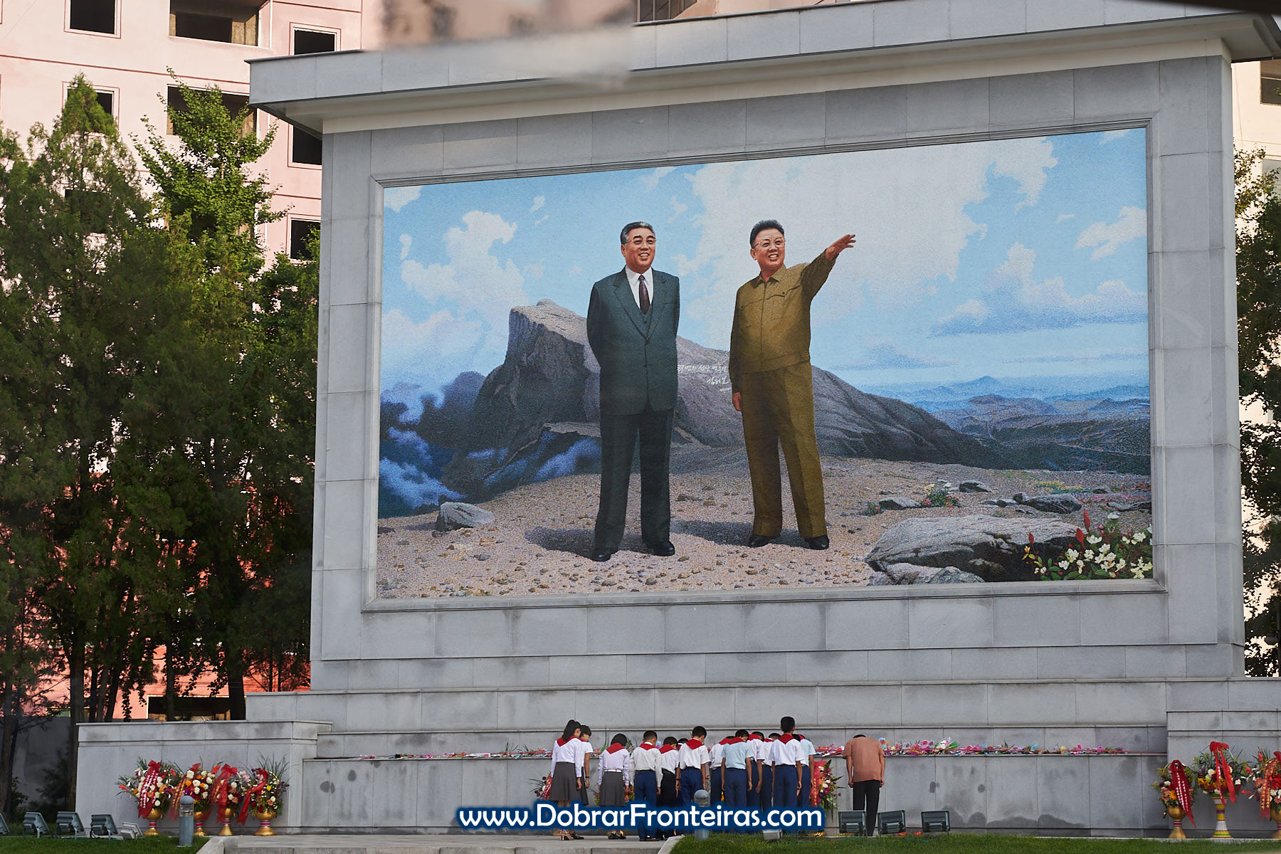 Pequenos Pioneiros junto a mural em Pyongyang