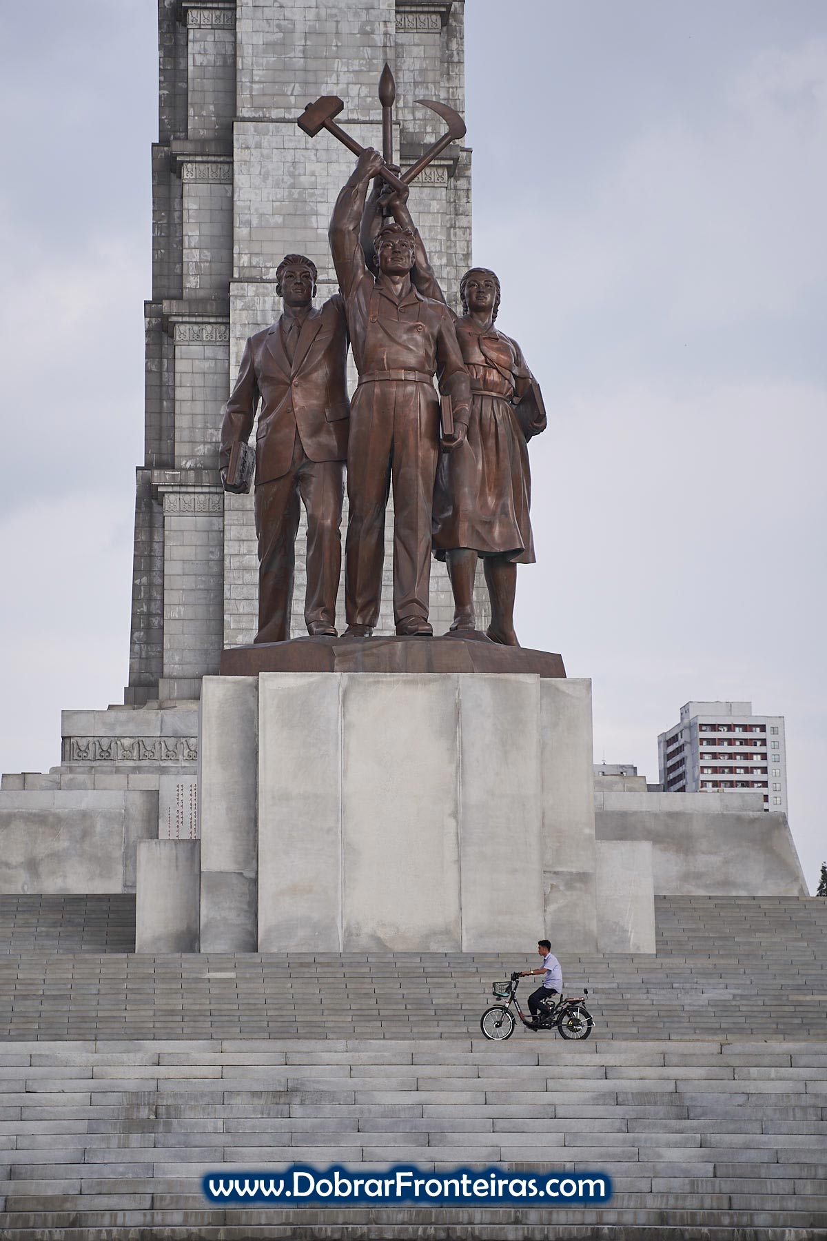Homem de moto em frente à Torre da ideia Juche
