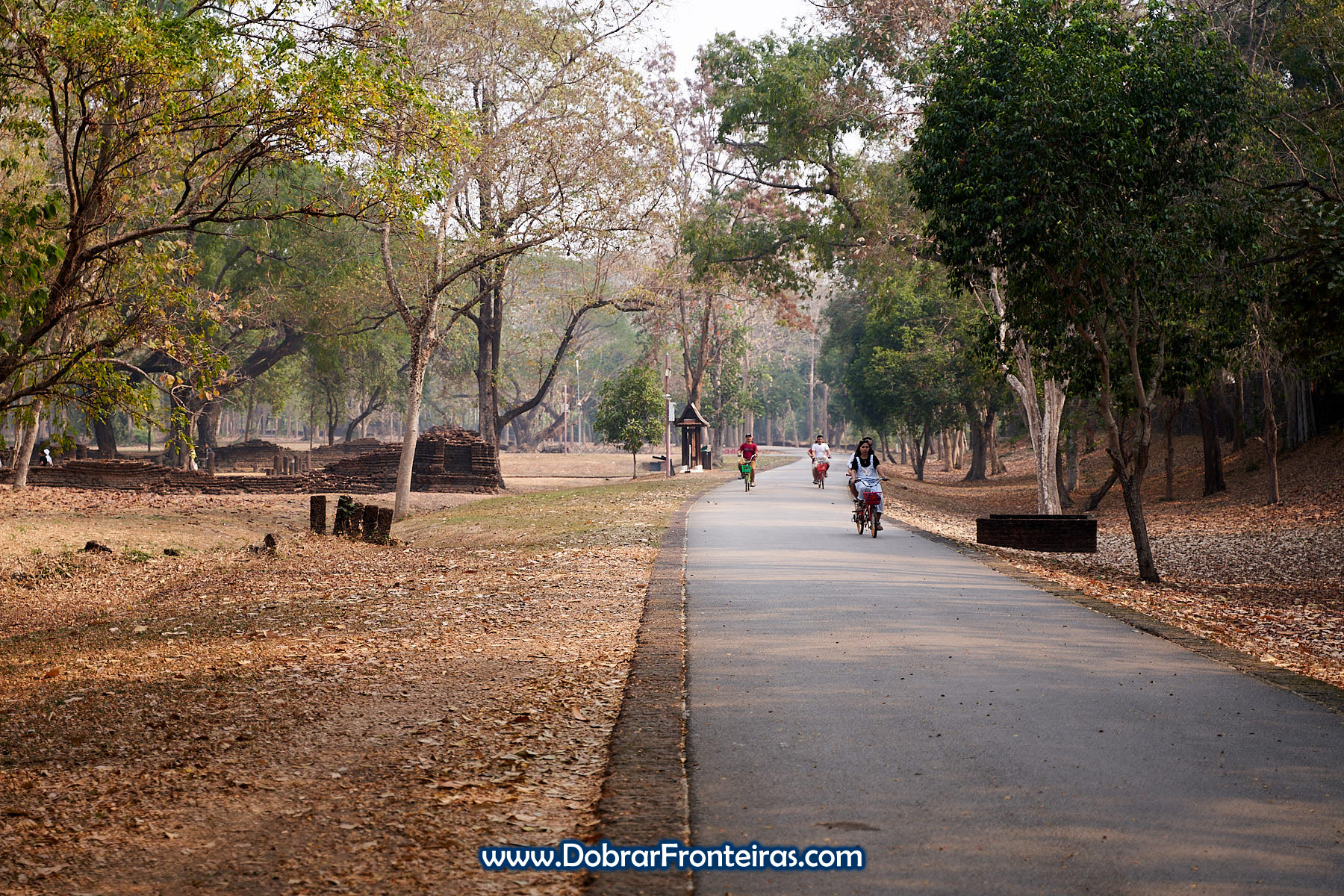 Pessoas de bicicleta nas ruínas de Si Satchanalai