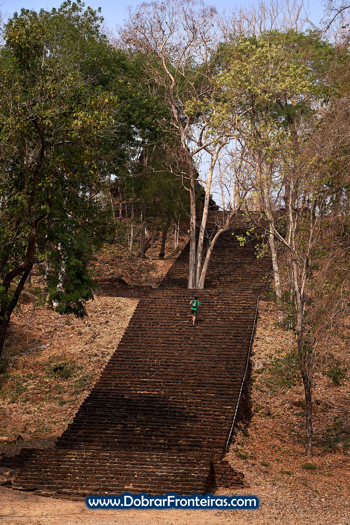 Homem a subir escada de pedra nas ruínas de Si Satchanalai